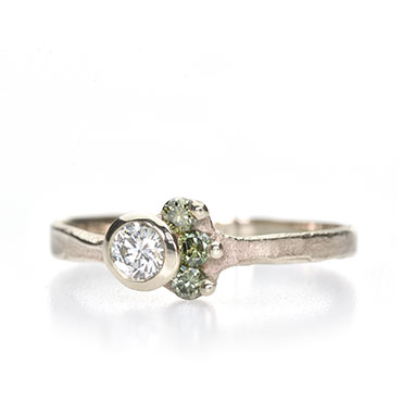 white gold ring with green colored diamonds